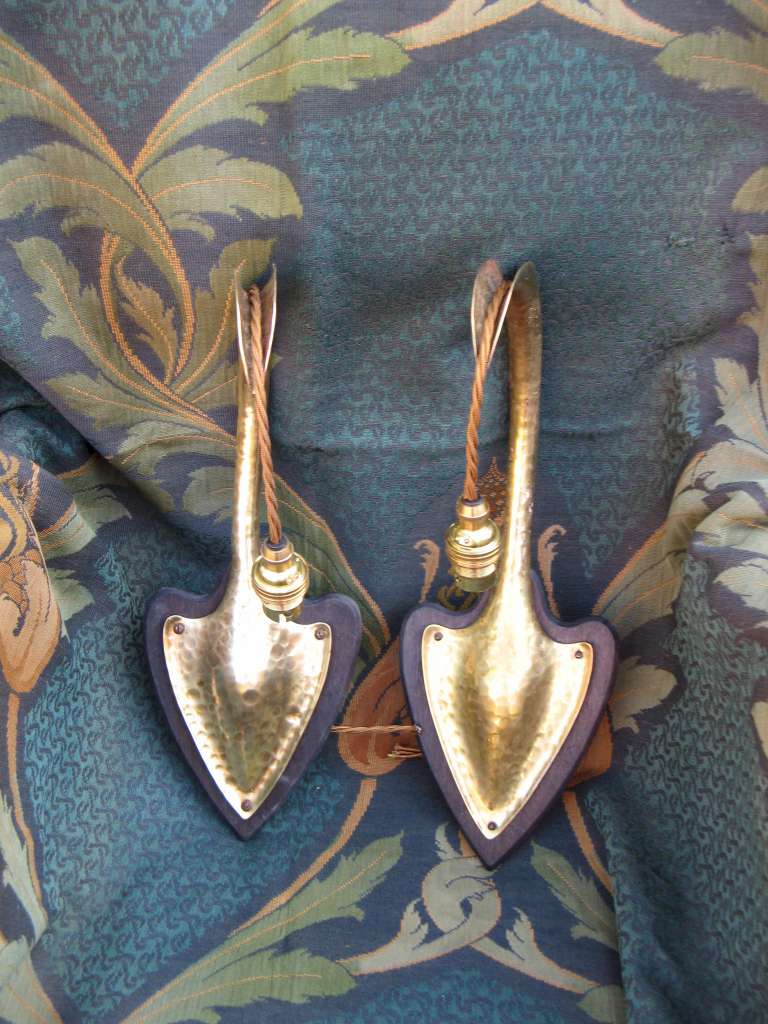 Pair of arts and crafts wall lights in hammered brass on wooden heart shaped backplates