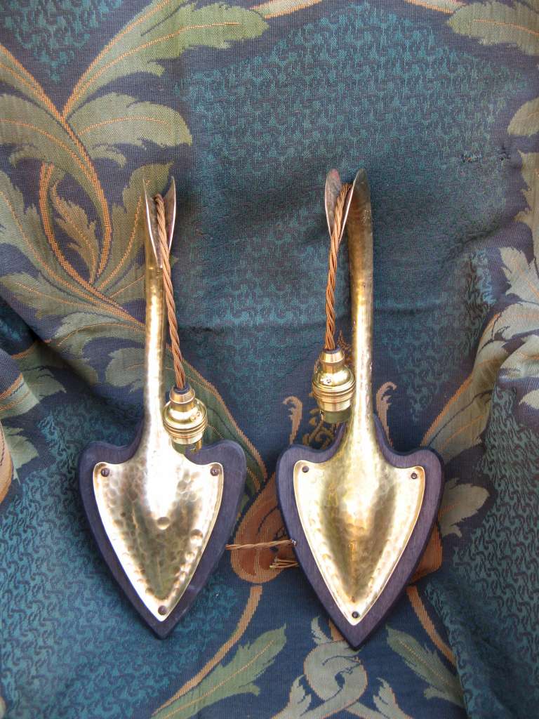 Pair of arts and crafts wall lights in hammered brass on wooden heart shaped backplates