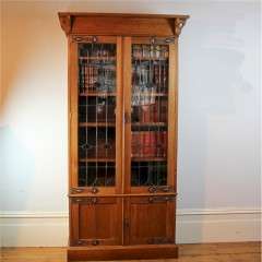 Arts and Crafts glazed bookcase in oak with coppered straps